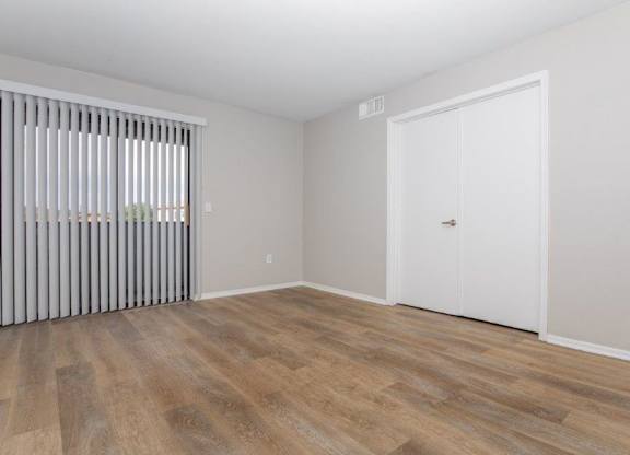 A room with a white door and a window with blinds.