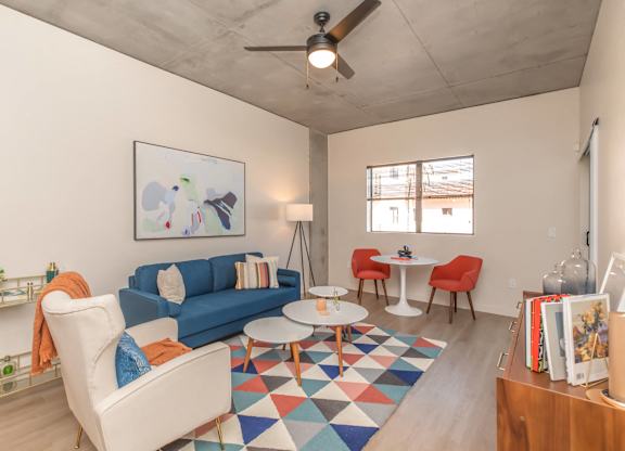 A living room with a blue couch, a white chair, and a small table.