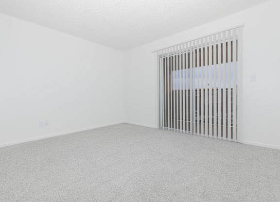 A room with a window covered by vertical blinds.