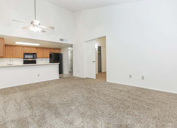 A room with a carpeted floor and a ceiling fan.