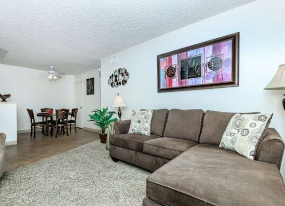 A living room with a brown couch and a painting on the wall.