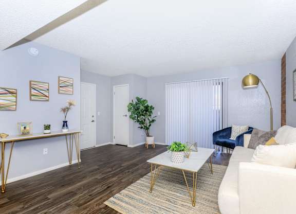 A living room with a white couch, a coffee table, and a blue chair.