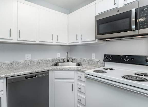 A kitchen with white cabinets and a granite countertop.