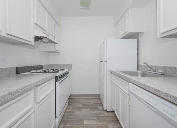 A white kitchen with a stove, oven, and refrigerator.