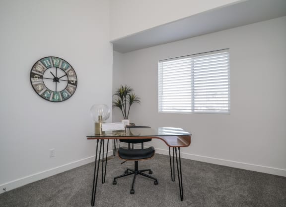 a small desk in a corner of a room with a large clock on the wall