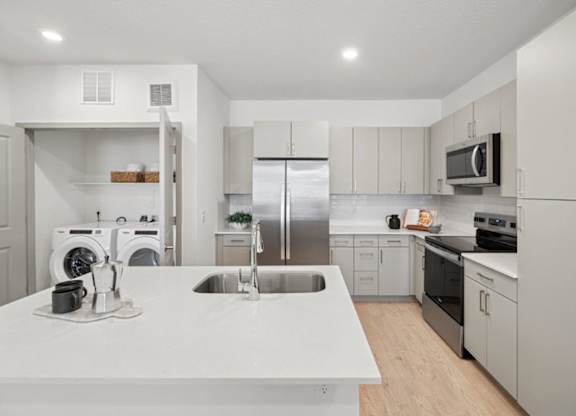 A modern kitchen with a white countertop and stainless steel appliances.