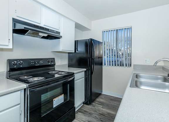 A black stove and refrigerator in a white kitchen.