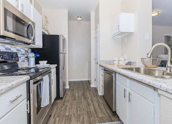 A kitchen with a black refrigerator and stove top oven.