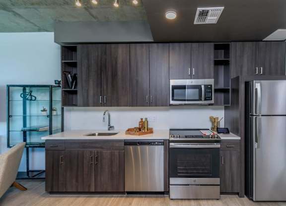 A modern kitchen with dark wood cabinets and stainless steel appliances.
