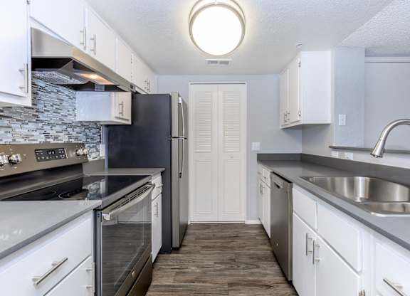 A kitchen with white cabinets and a black refrigerator.