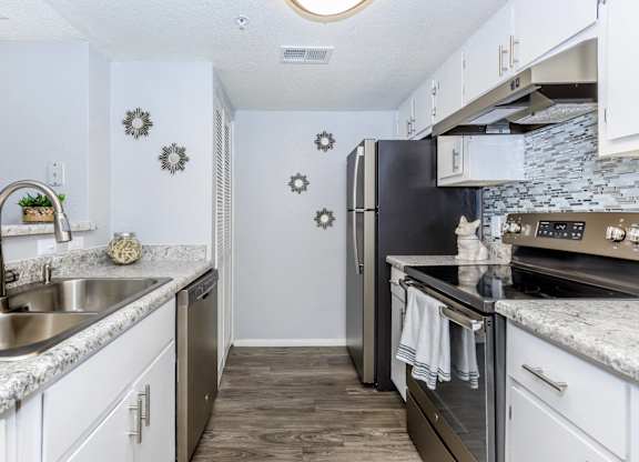 A kitchen with a black refrigerator and stove top oven.