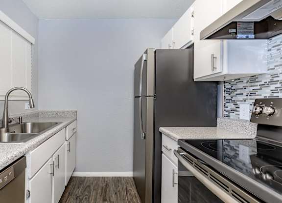 A kitchen with a stainless steel refrigerator and a stove top oven.