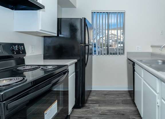 A black stove top oven sits next to a black refrigerator in a kitchen.