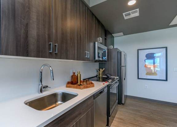 A modern kitchen with dark wood cabinets and stainless steel appliances.