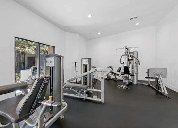A gym with a variety of equipment including a leg press machine, a chest press machine, a leg curl machine, a leg extension machine, a seated calf raise machine, a leg press machine, a leg curl machine, a ch