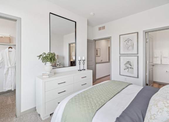 A white bedroom with a large bed and a mirror on the wall.