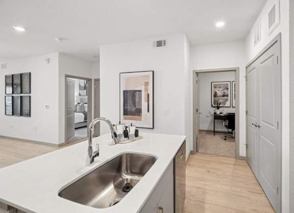 A modern kitchen with a white countertop and a stainless steel sink.