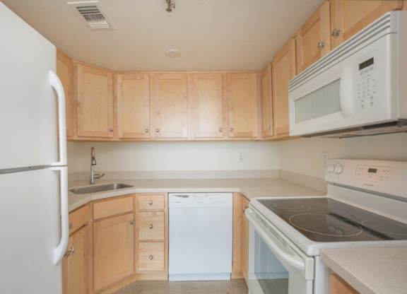 A kitchen with wooden cabinets and white appliances at Herbert Residential, Tucson, AZ