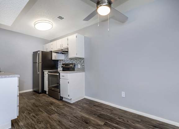 A kitchen with a refrigerator, oven, and cabinets.