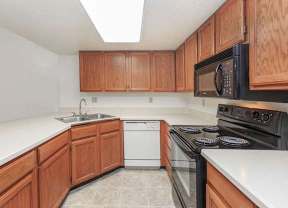 A kitchen with wooden cabinets and a black microwave above the stove.