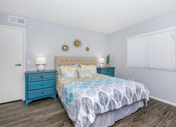 A bedroom with a blue bed and a white wall.