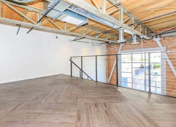 A room with wooden floors and a brick wall with a window.