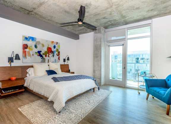A bedroom with a bed, a chair, and a painting on the wall.