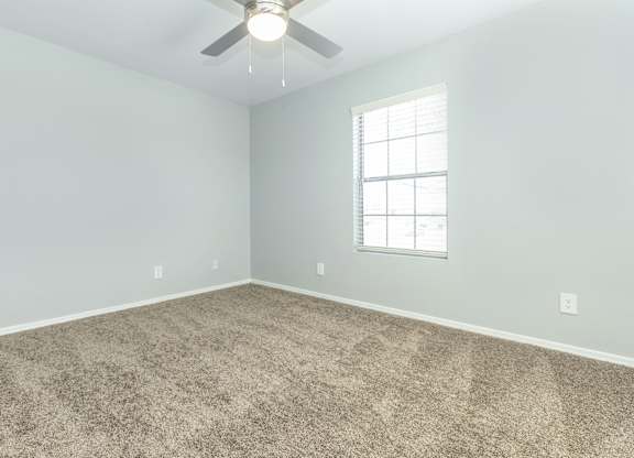 A room with a ceiling fan and a window.