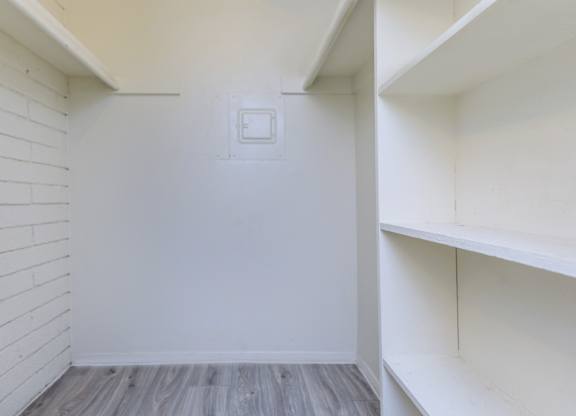 A white wall with a light switch and a wooden floor.