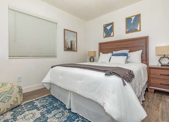 A bedroom with a large bed and a window with blinds.
