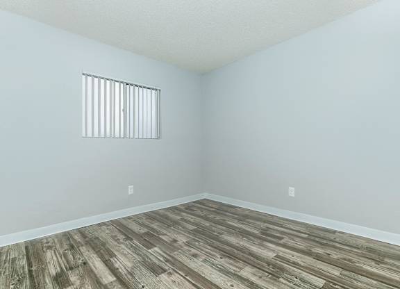 A room with a window and wooden flooring.