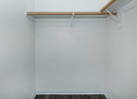 A white wall with a shelf and a wooden floor.