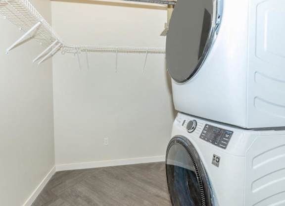 A white dryer is in a laundry room with a white wall and a white hanger.