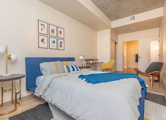 A bedroom with a blue bedspread and a bed with a blue headboard.