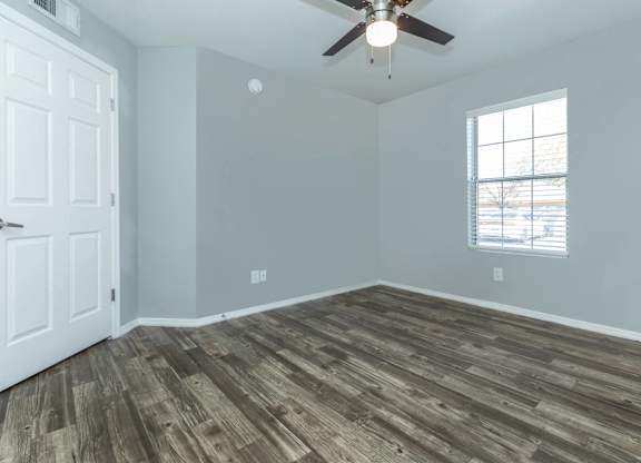 A room with a ceiling fan and a window with blinds.