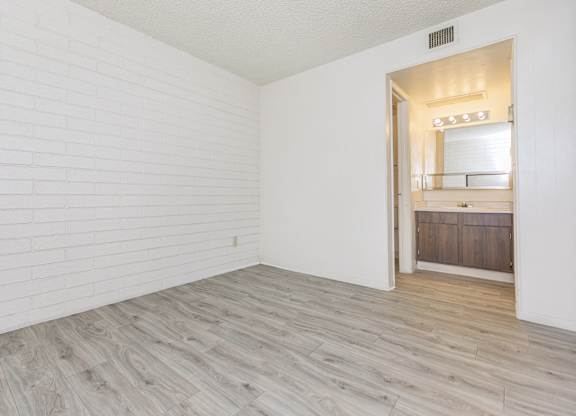 A room with a white brick wall and wooden flooring.