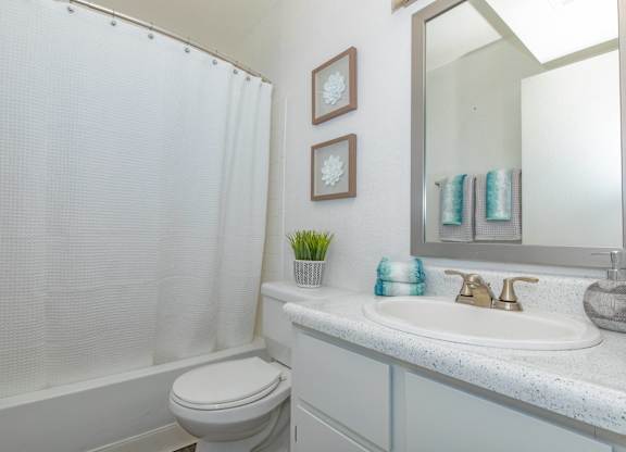 A white bathroom with a toilet, sink, and shower.