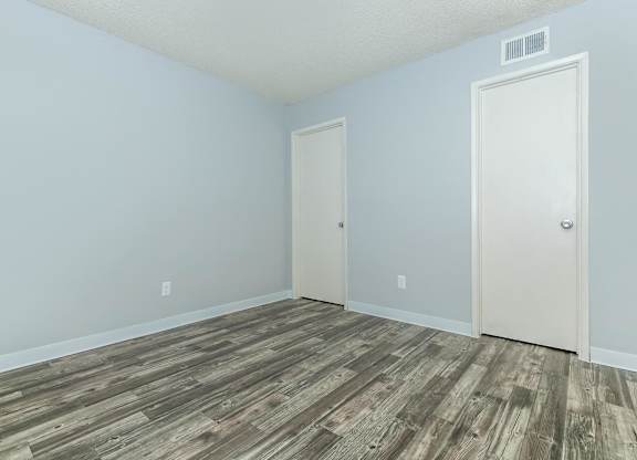 A room with a wooden floor and two doors.