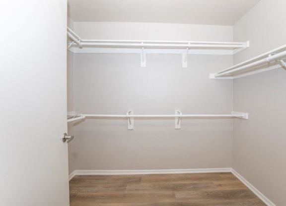 A white closet with a door and shelves.