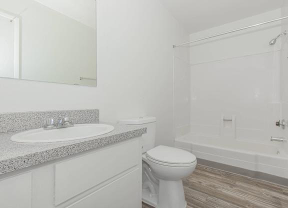 A white bathroom with a toilet, sink, and bathtub.