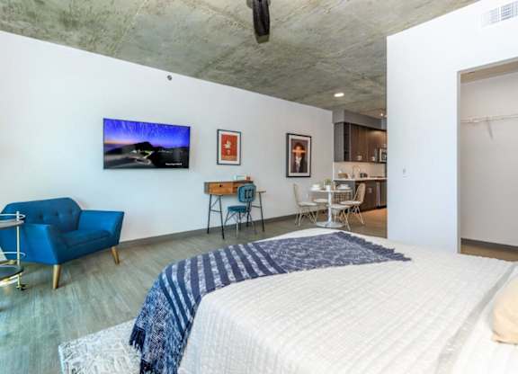A bedroom with a bed, a chair, and a television on the wall.