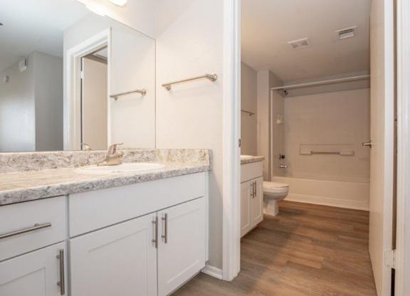 A bathroom with a marble countertop and white cabinets.