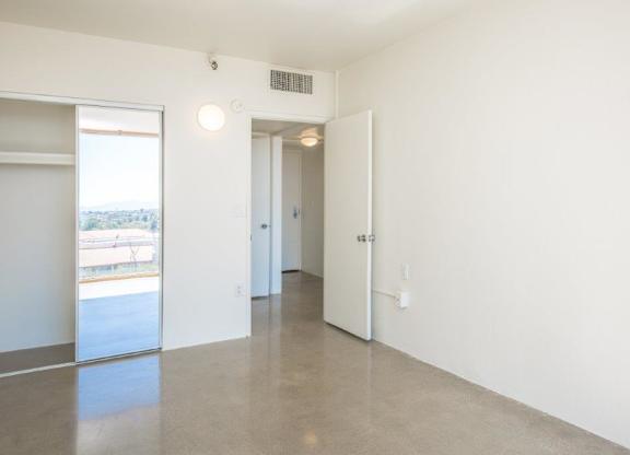 A large, empty room with a sliding glass door and a white door at Herbert Residential, Tucson