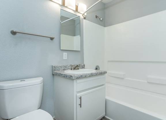 A white bathroom with a toilet, sink, and bathtub.