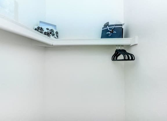 A white shelf with a black hanger on it.