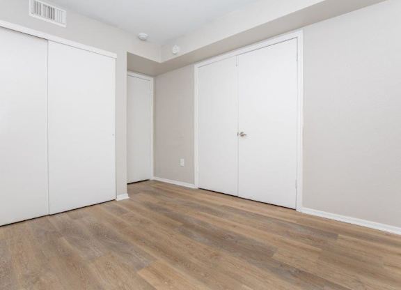 A room with two white doors and a wooden floor.