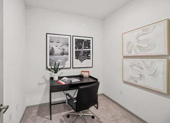 A black and white photo is on the wall above a black desk.