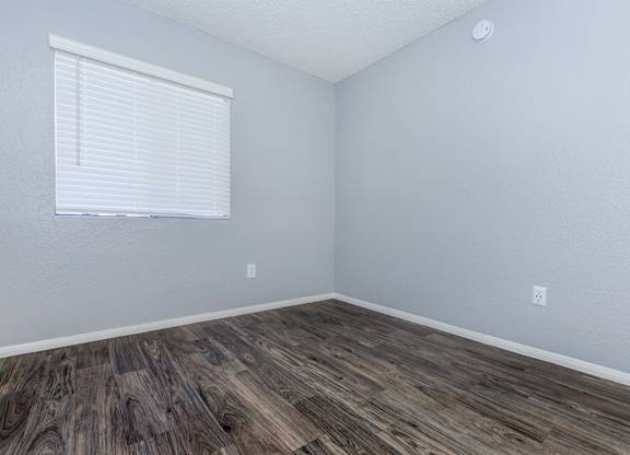 A room with wooden flooring and a window with blinds.