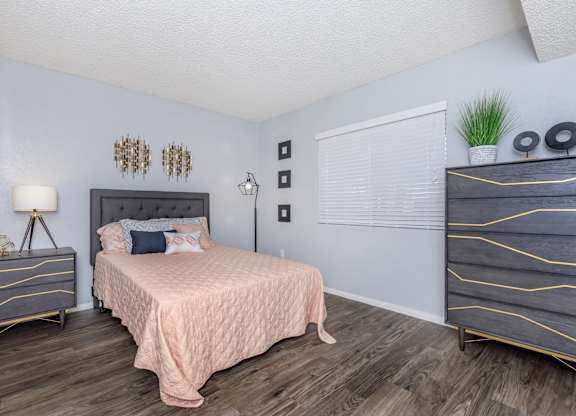 A bedroom with a bed, nightstand, and dresser.