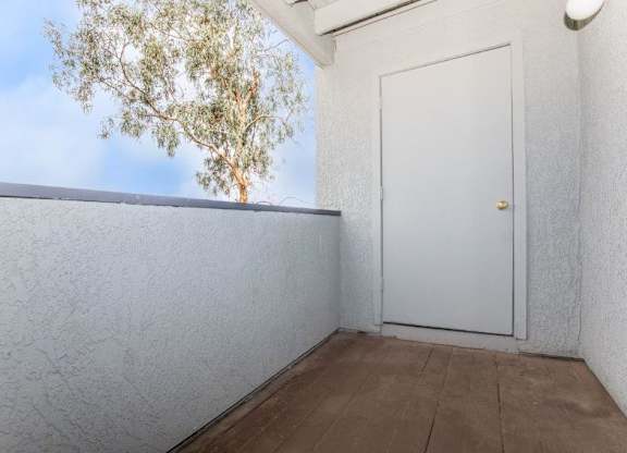 A white door is closed in a room with a brown floor.